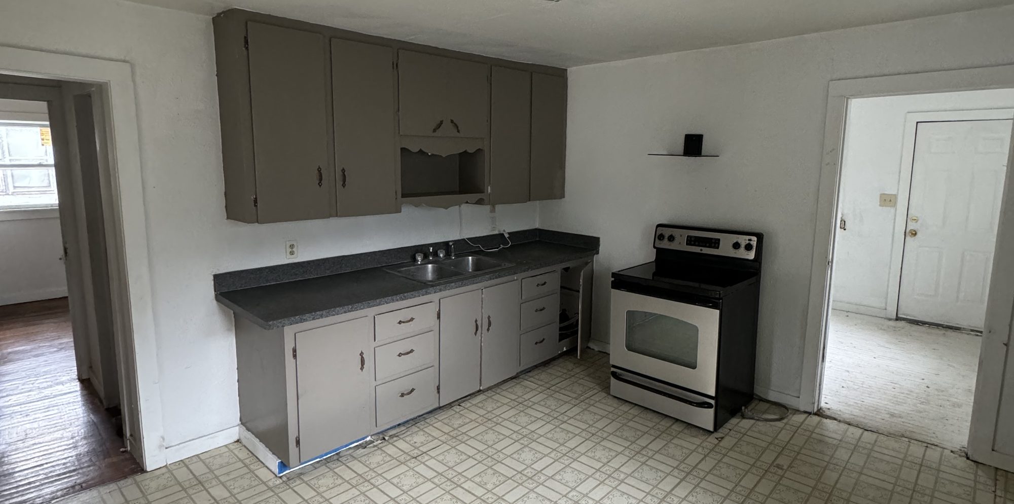 The kitchen as found: original cabinets, sheet flooring, and a wall closing the room off