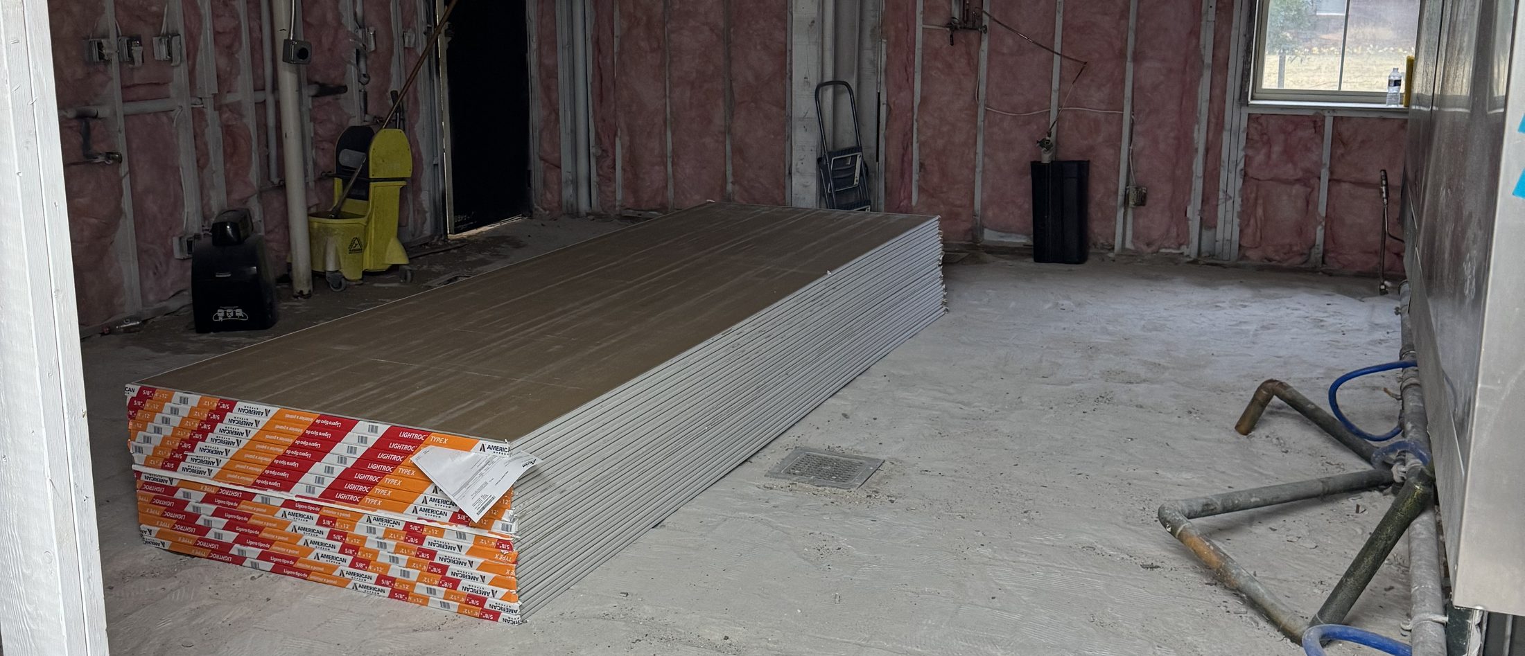 A commercial interior stripped to the framing and joists, mid build-out