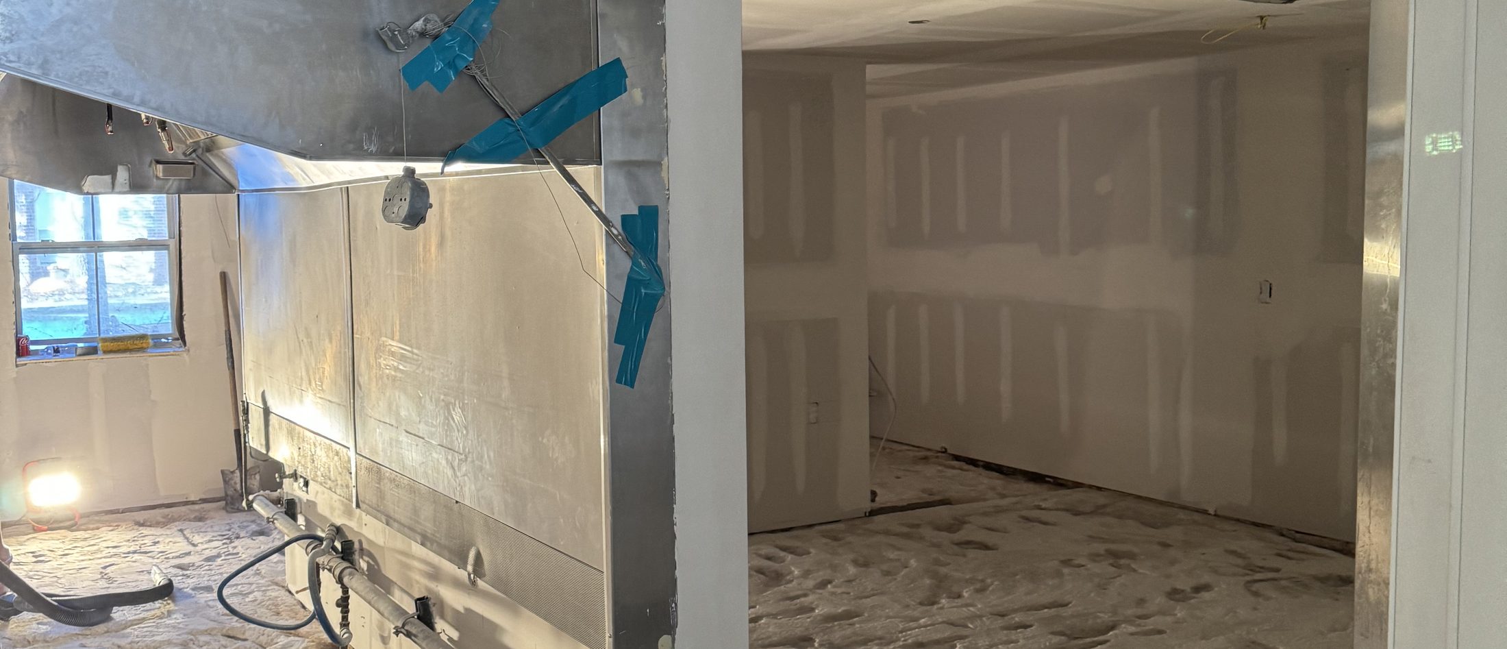 A tradesman working along a drywalled wall on a commercial job